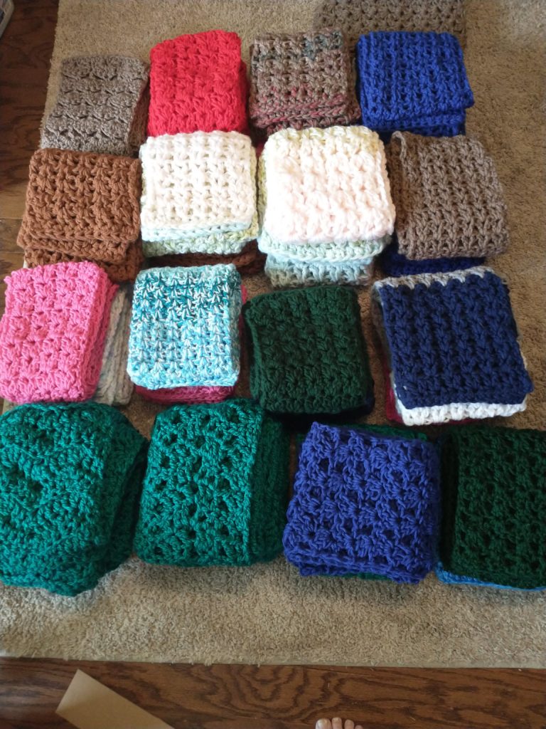 Stack of 33 crocheted scarves in a variety of colors 
